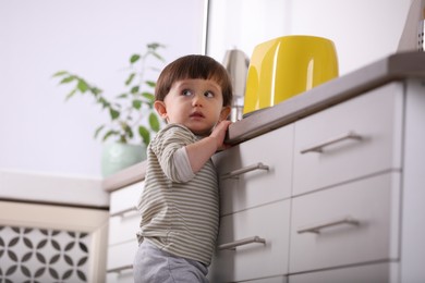 Photo of Little boy playing with toaster in kitchen, low angle view . Dangerous situation