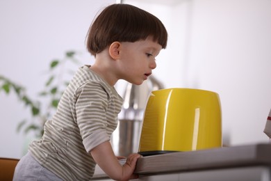 Photo of Little boy playing with toaster in kitchen. Dangerous situation