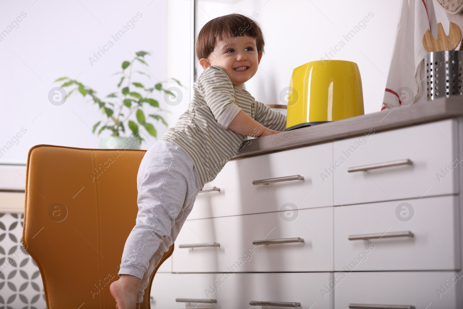 Photo of Little boy playing with toaster in kitchen. Dangerous situation