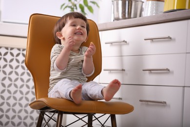 Photo of Little boy playing on chair in kitchen. Dangerous situation