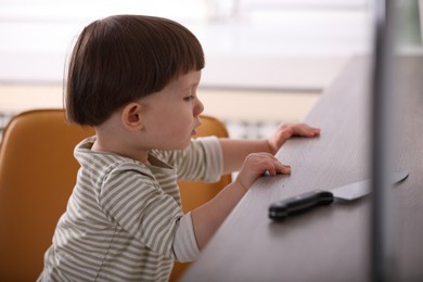 Photo of Little boy reaching towards knife on kitchen counter. Dangerous situation