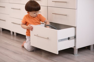 Photo of Little boy playing with kitchen appliances indoors. Dangerous situation