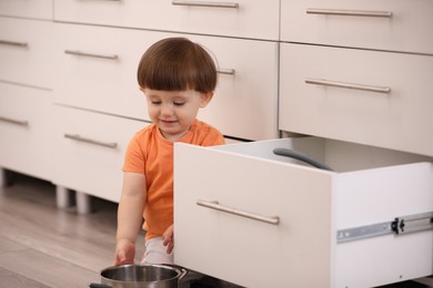 Photo of Little boy playing with kitchen appliances indoors. Dangerous situation