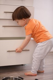 Photo of Little boy playing with kitchen appliances indoors. Dangerous situation