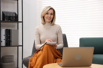 Professional psychologist working with notebook and laptop in office