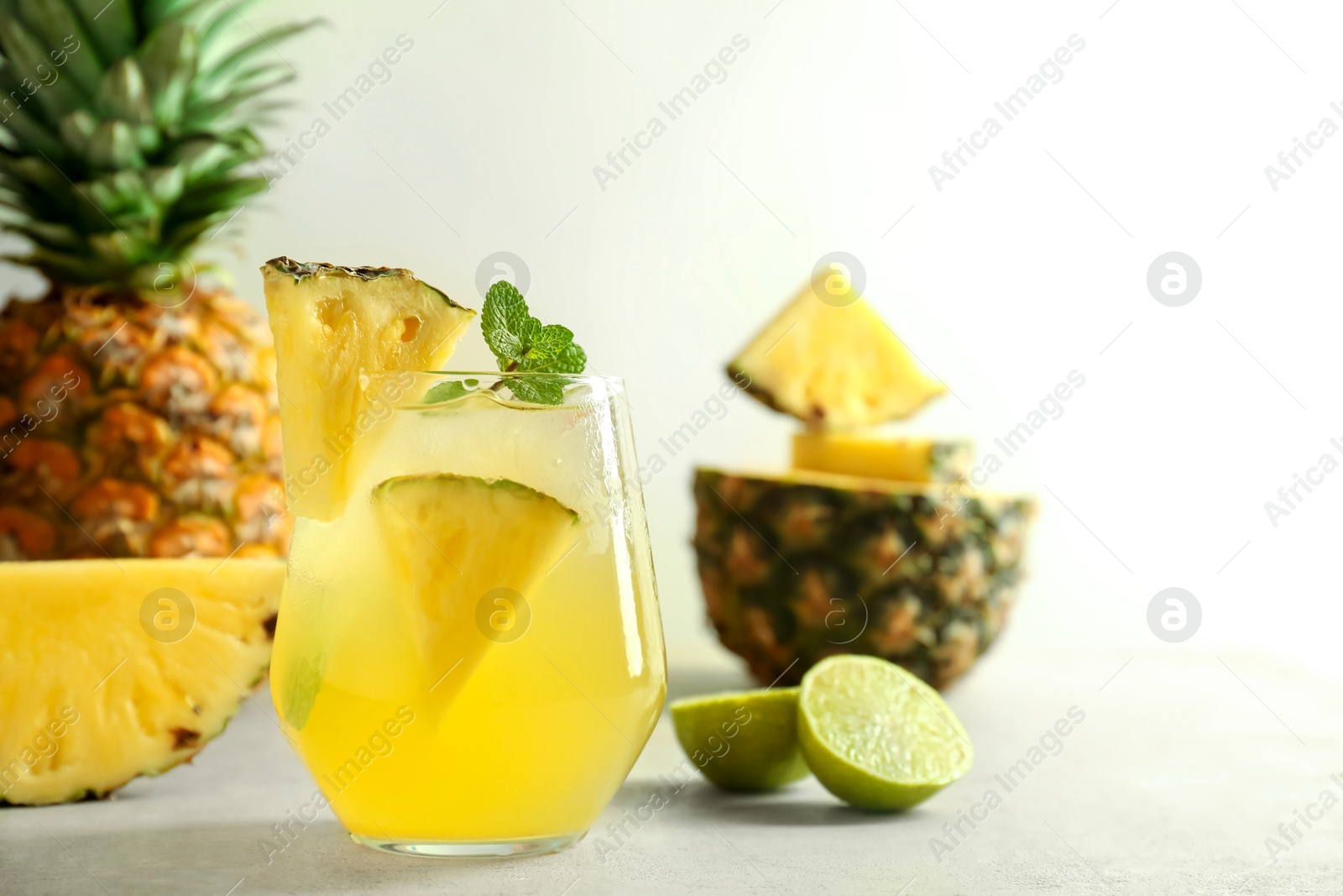 Photo of Tasty pineapple cocktail with mint in glass on light table