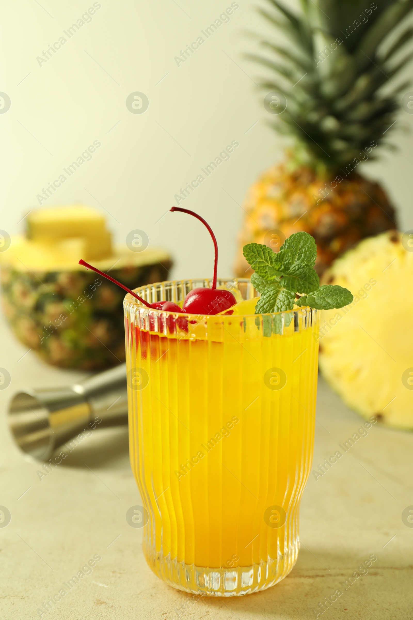 Photo of Tasty pineapple cocktail with mint and cherry in glass served on light table