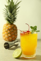 Photo of Tasty pineapple cocktail with mint and cherry in glass served on light table