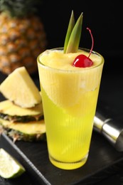 Photo of Tasty pineapple cocktail with cherry in glass on black table, closeup