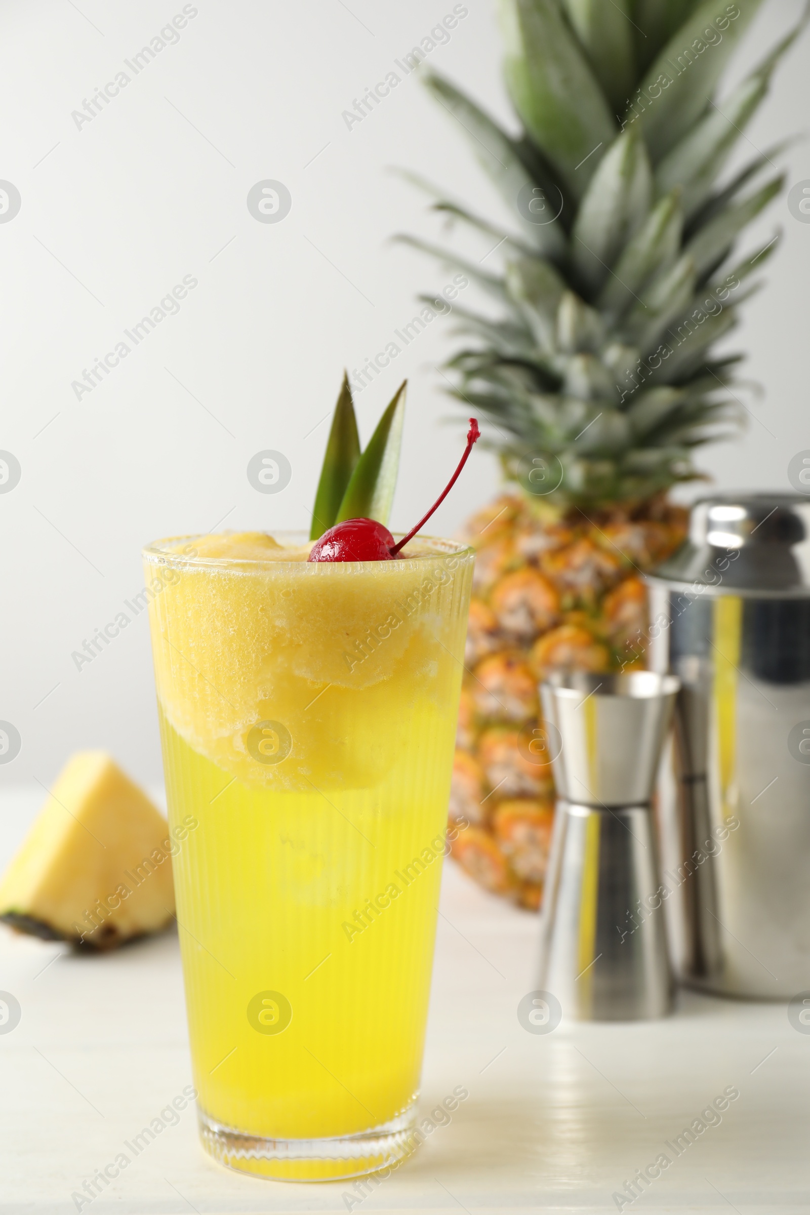 Photo of Tasty pineapple cocktail with cherry in glass on light table