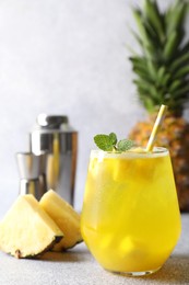 Photo of Tasty pineapple cocktail with mint in glass on gray table