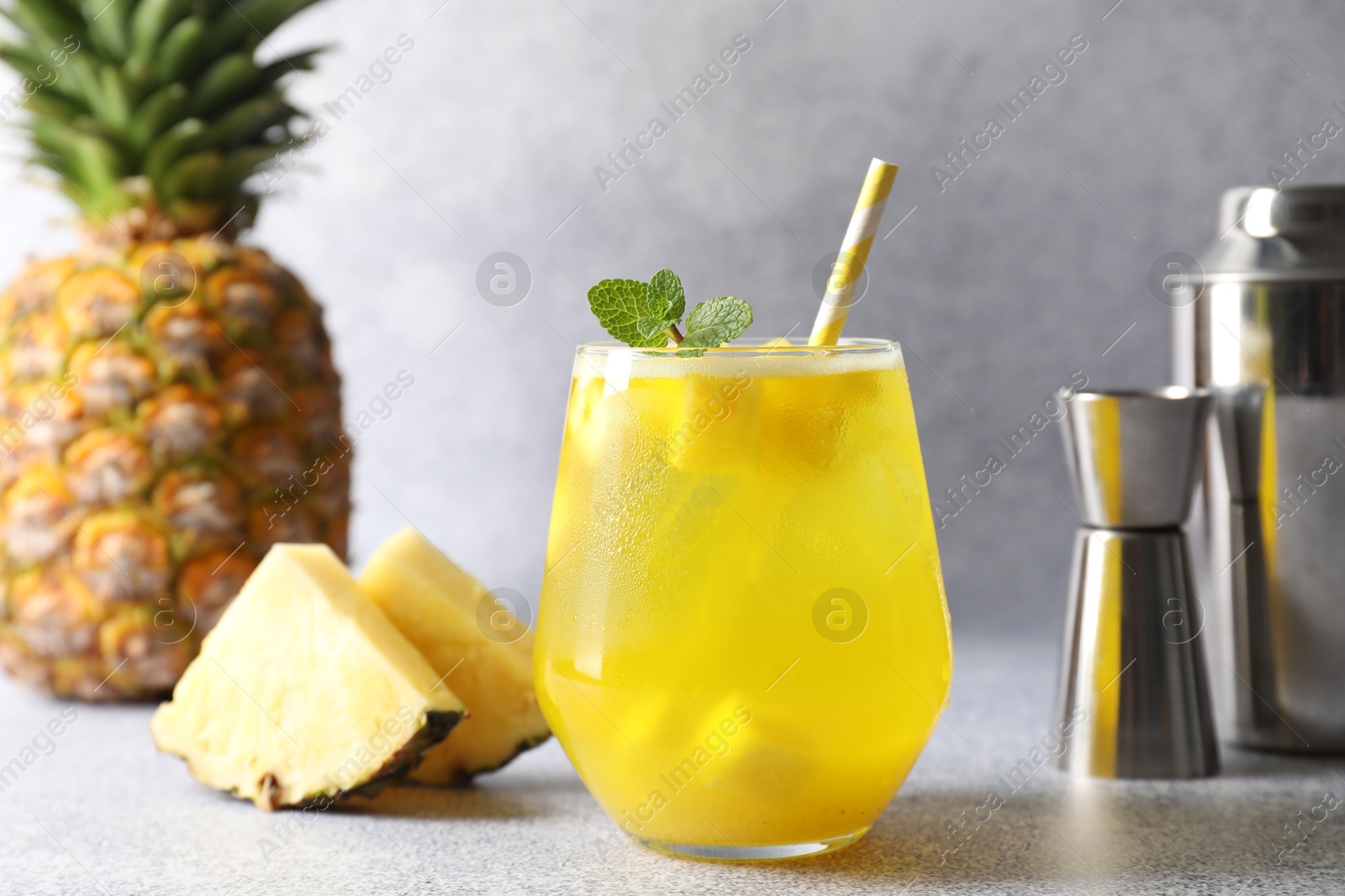 Photo of Tasty pineapple cocktail with mint in glass on gray table