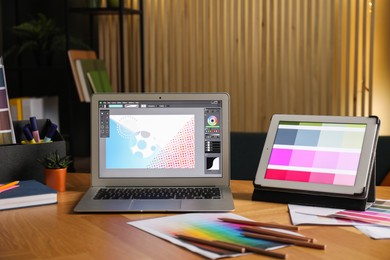 Photo of Designer's workplace with laptop, tablet, stationery and palettes on wooden table indoors