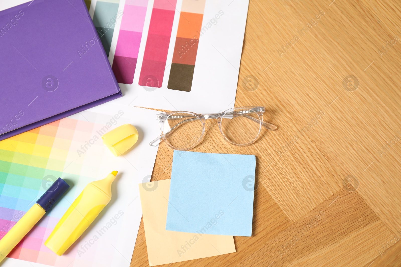 Photo of Designer's workplace with different color palettes and stationery on wooden table, top view