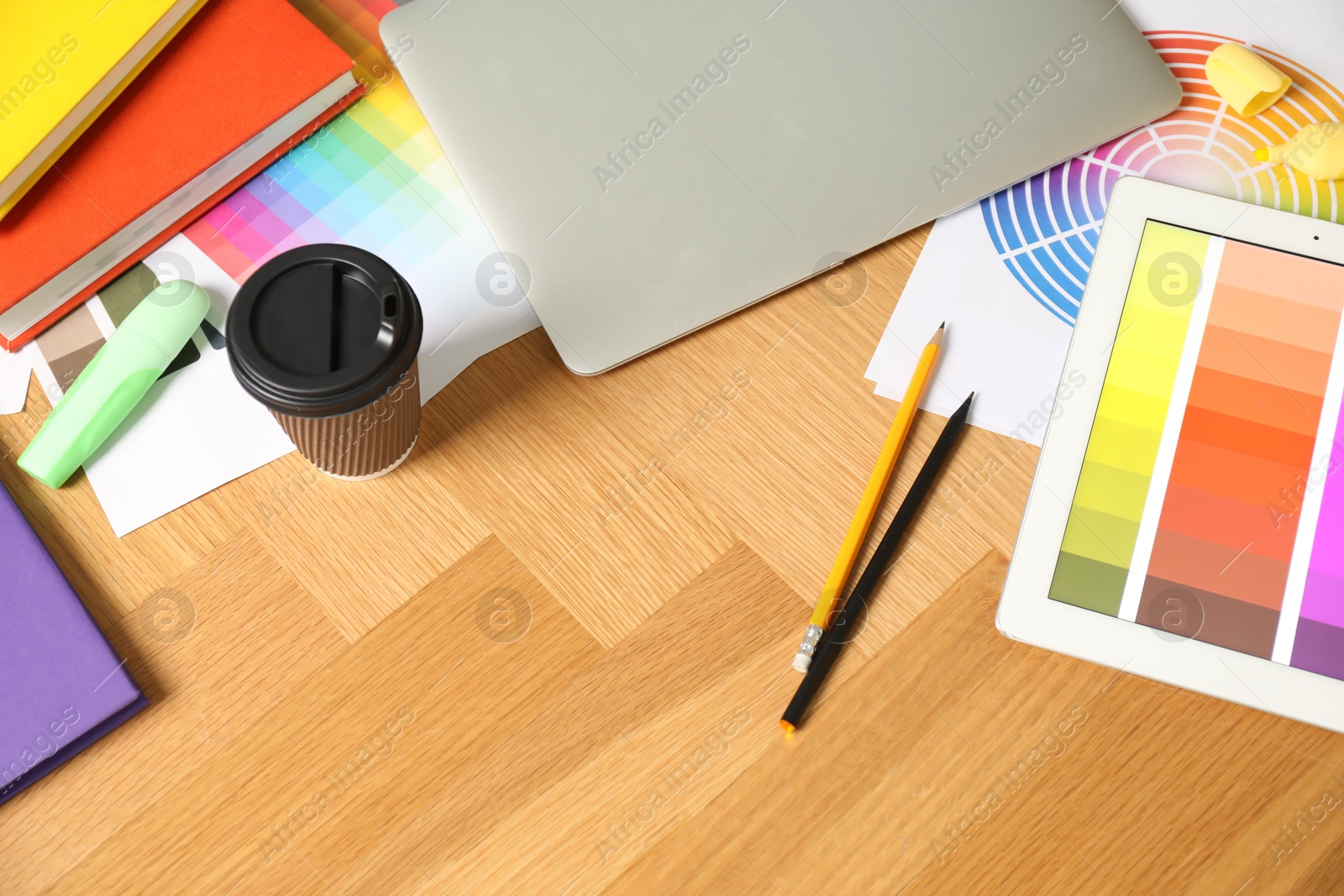 Photo of Designer's workplace with laptop, tablet, palettes and stationery on wooden table, above view