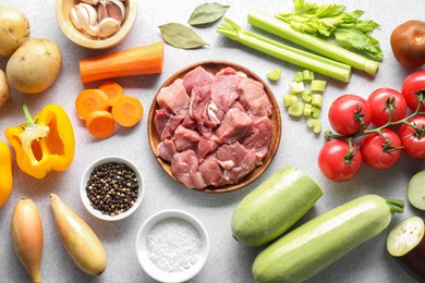 Cooking stew. Uncooked meat and vegetables on light grey table, flat lay