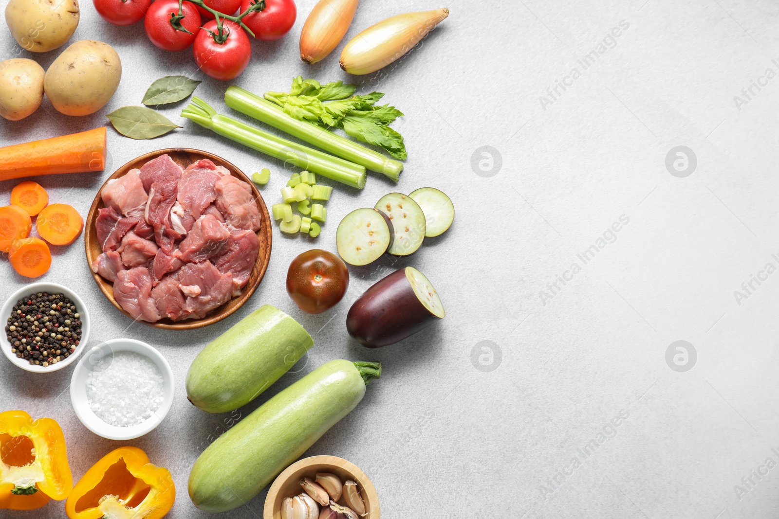 Photo of Cooking stew. Uncooked meat and vegetables on light grey table, flat lay. Space for text