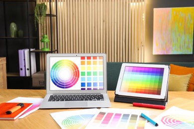 Photo of Designer's workplace with laptop, tablet, stationery and palettes on wooden table indoors