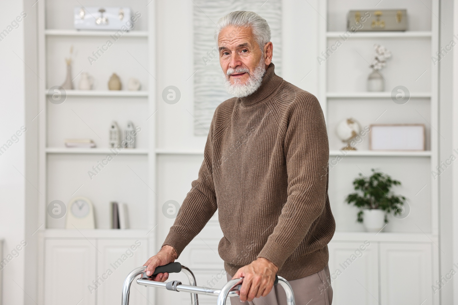 Photo of Senior man using walking frame at home