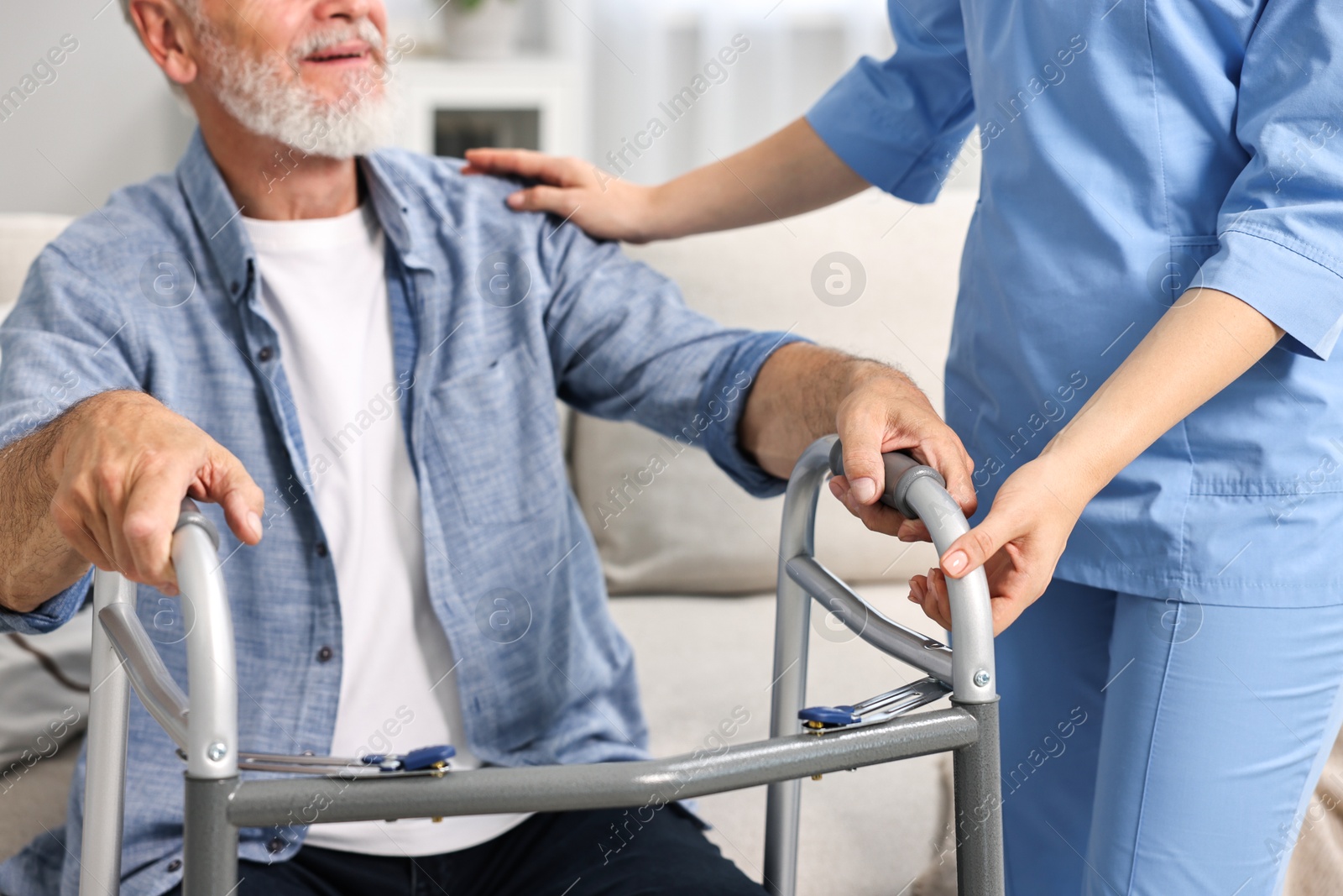 Photo of Nurse helping senior man with walking frame indoors, closeup