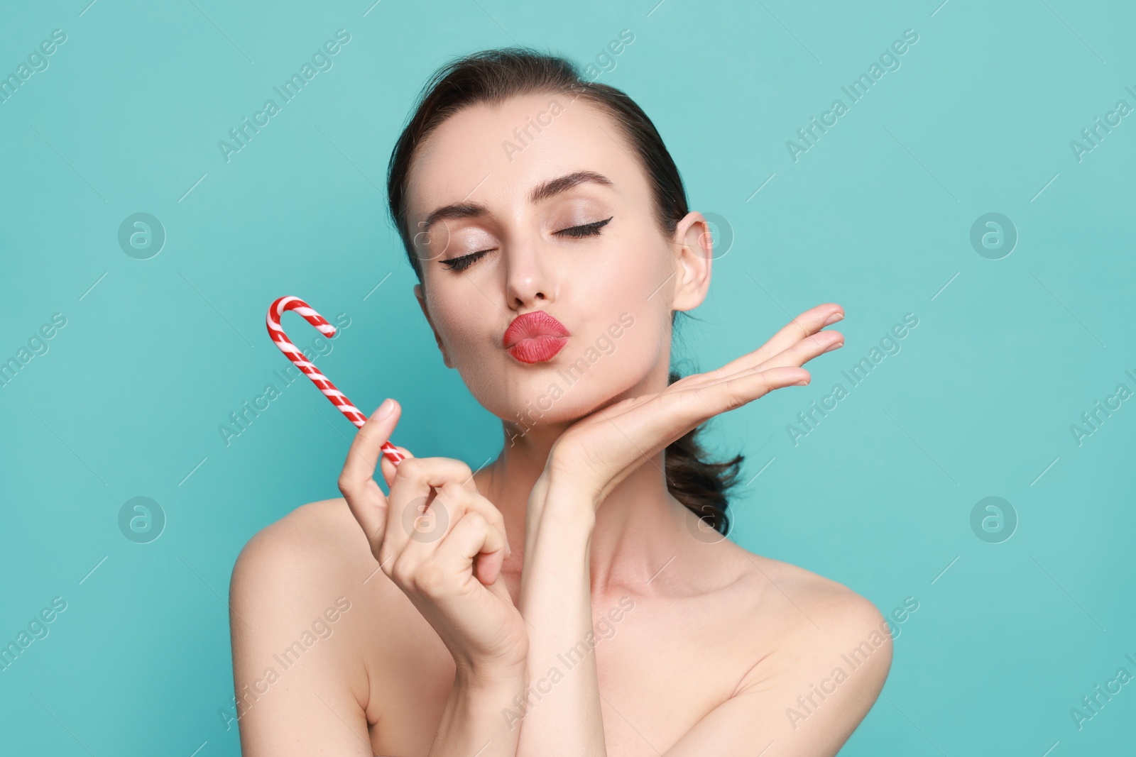 Photo of Woman with Christmas candy cane on light blue background