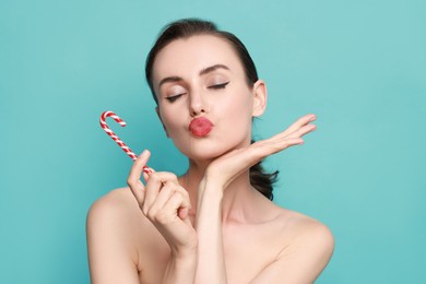 Photo of Woman with Christmas candy cane on light blue background