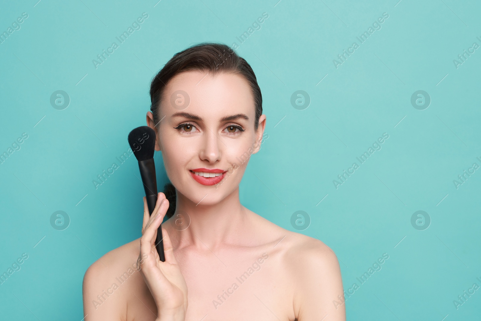 Photo of Smiling woman with makeup brush on light blue background. Space for text