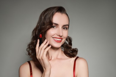 Photo of Smiling woman with red lipstick on grey background