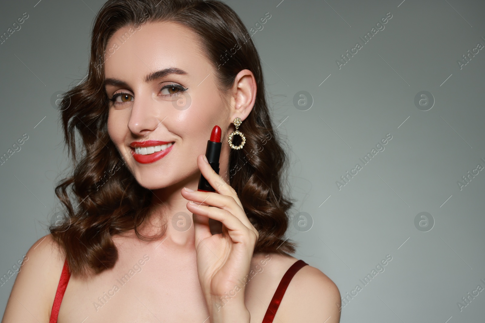 Photo of Smiling woman with red lipstick on grey background. Space for text