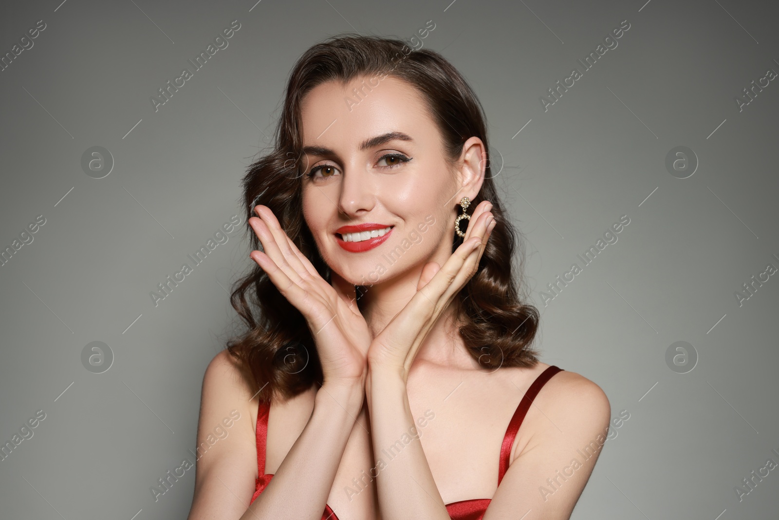 Photo of Portrait of smiling woman with perfect makeup on grey background