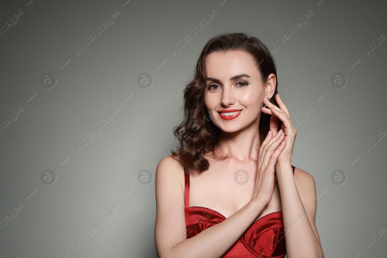 Photo of Portrait of smiling woman with perfect makeup on grey background. Space for text