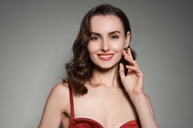 Photo of Portrait of smiling woman with perfect makeup on grey background