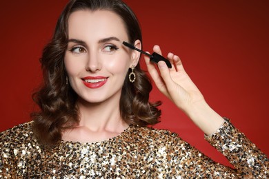 Smiling woman with makeup brush on red background