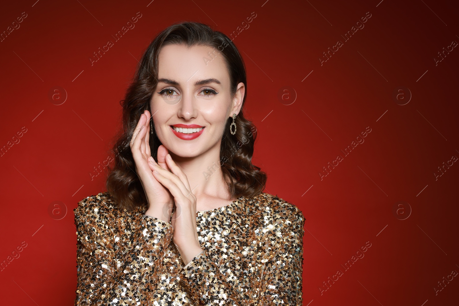 Photo of Smiling woman with perfect makeup on red background. Space for text