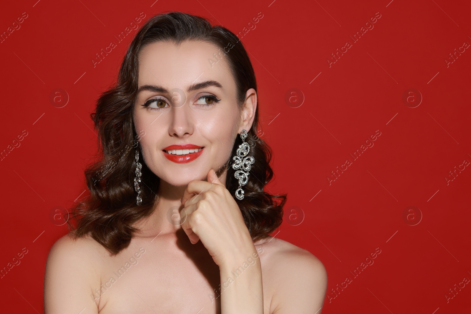 Photo of Smiling woman with perfect makeup on red background. Space for text