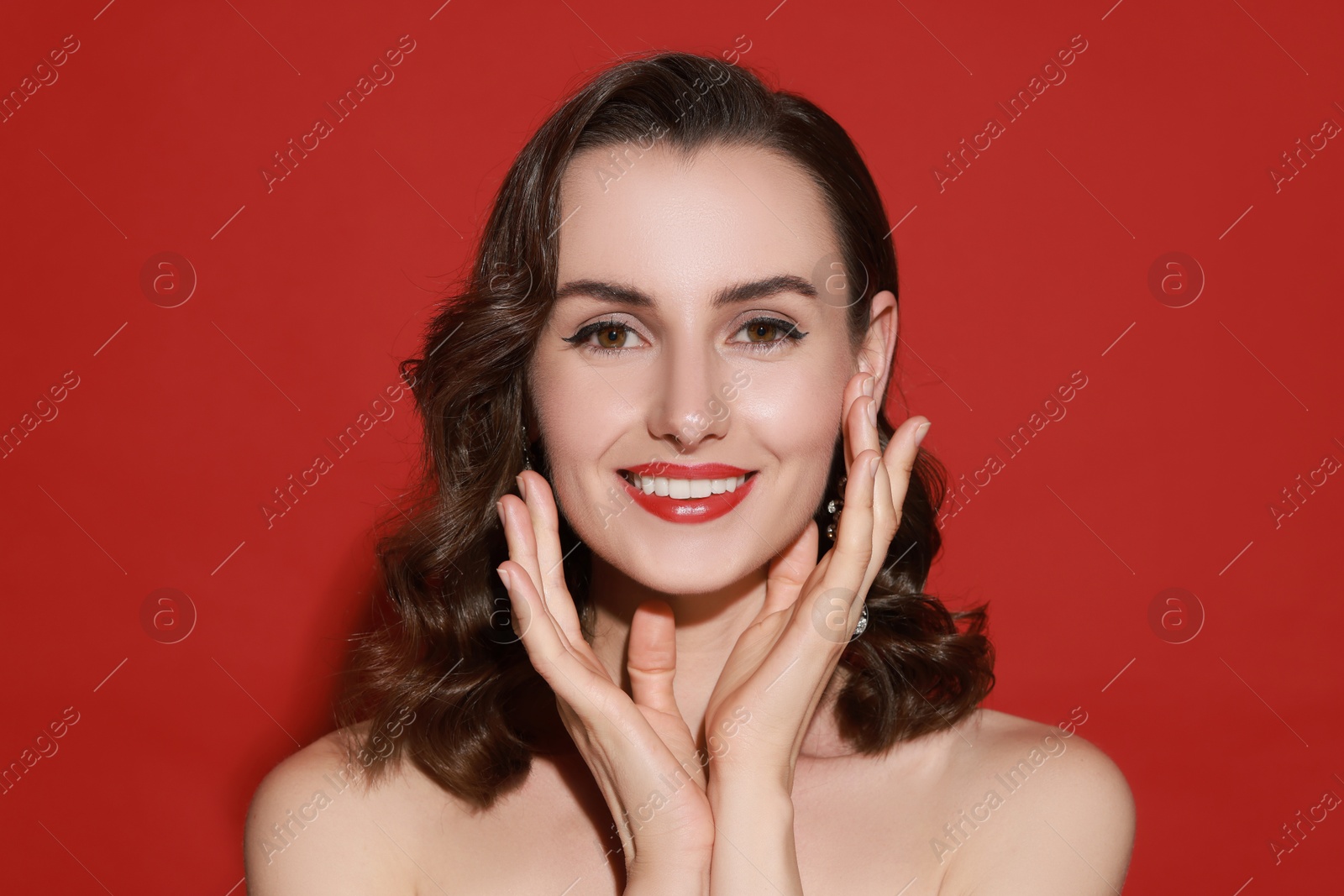 Photo of Smiling woman with perfect makeup on red background