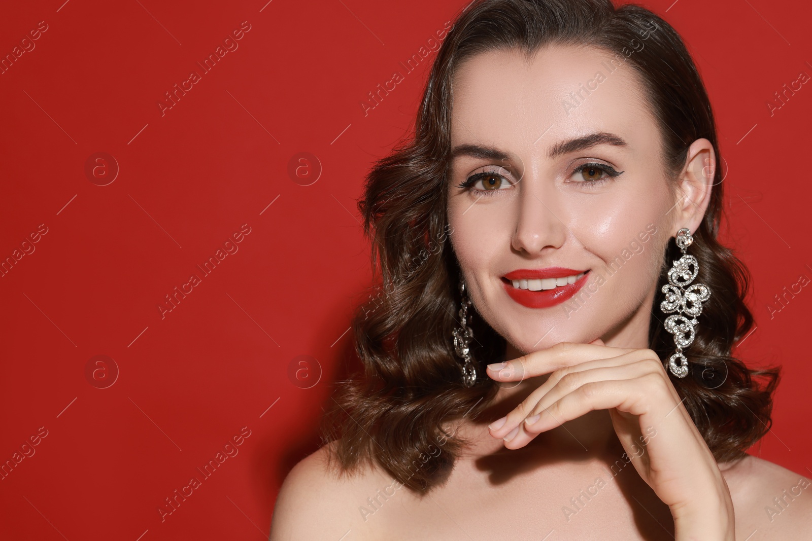 Photo of Smiling woman with perfect makeup on red background. Space for text