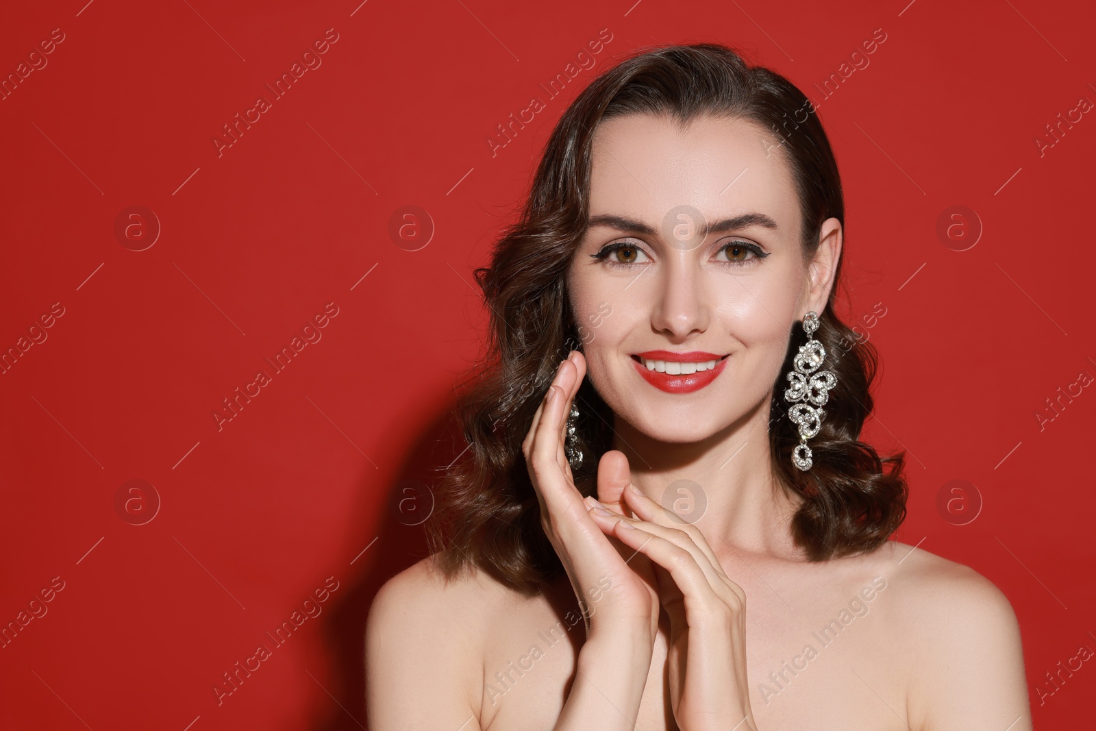 Photo of Smiling woman with perfect makeup on red background. Space for text