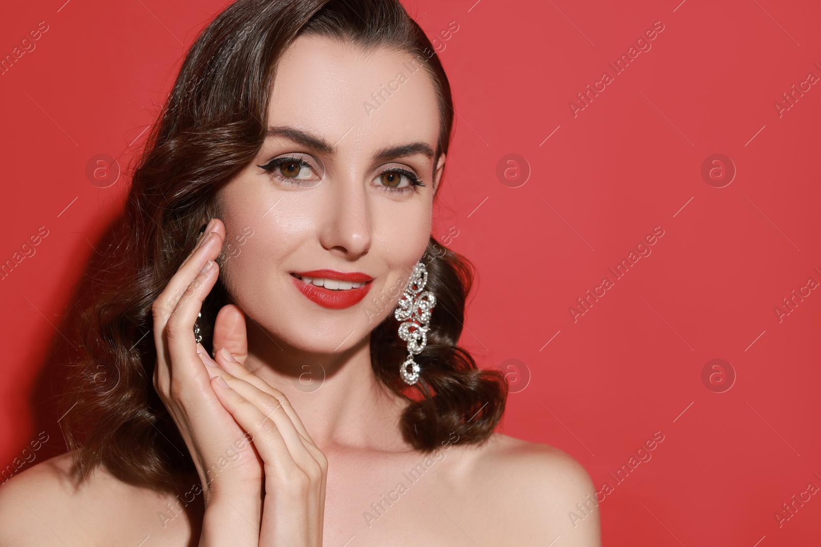 Photo of Smiling woman with perfect makeup on red background. Space for text