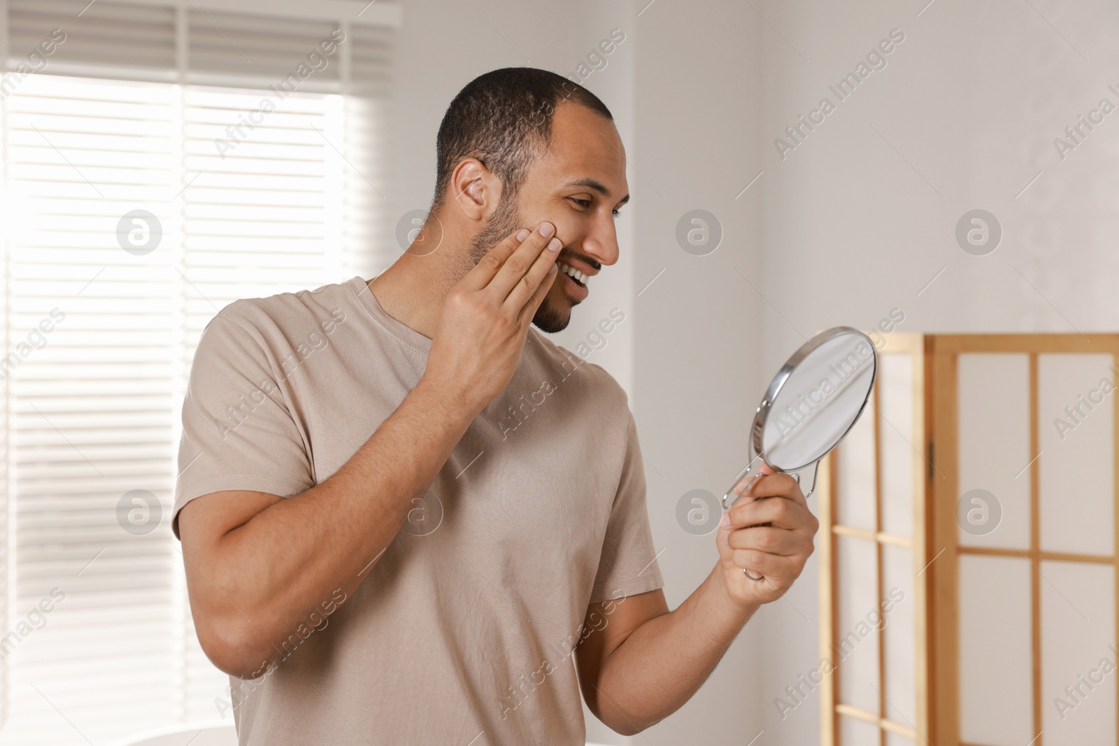 Photo of Smiling man looking at mirror in room