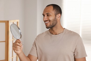 Photo of Smiling man looking at mirror in room