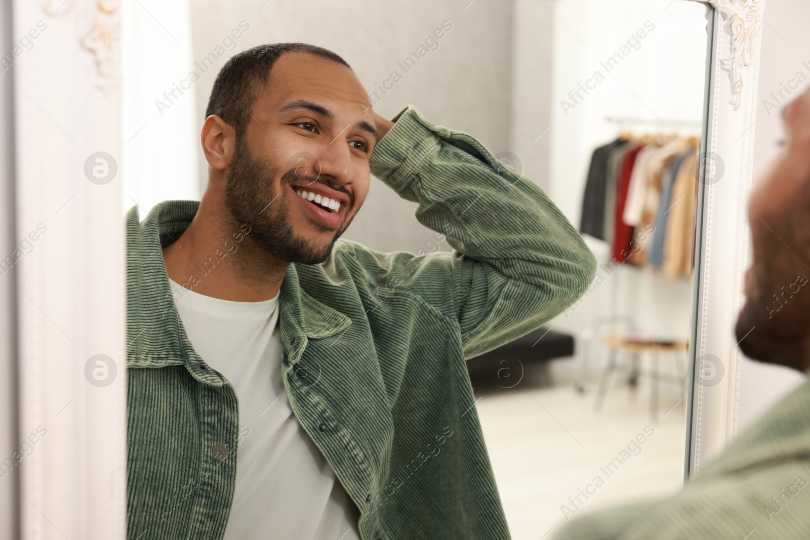 Photo of Smiling man looking at mirror at home