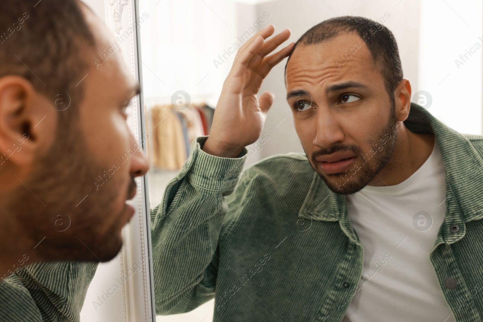 Photo of Worried man looking at mirror at home