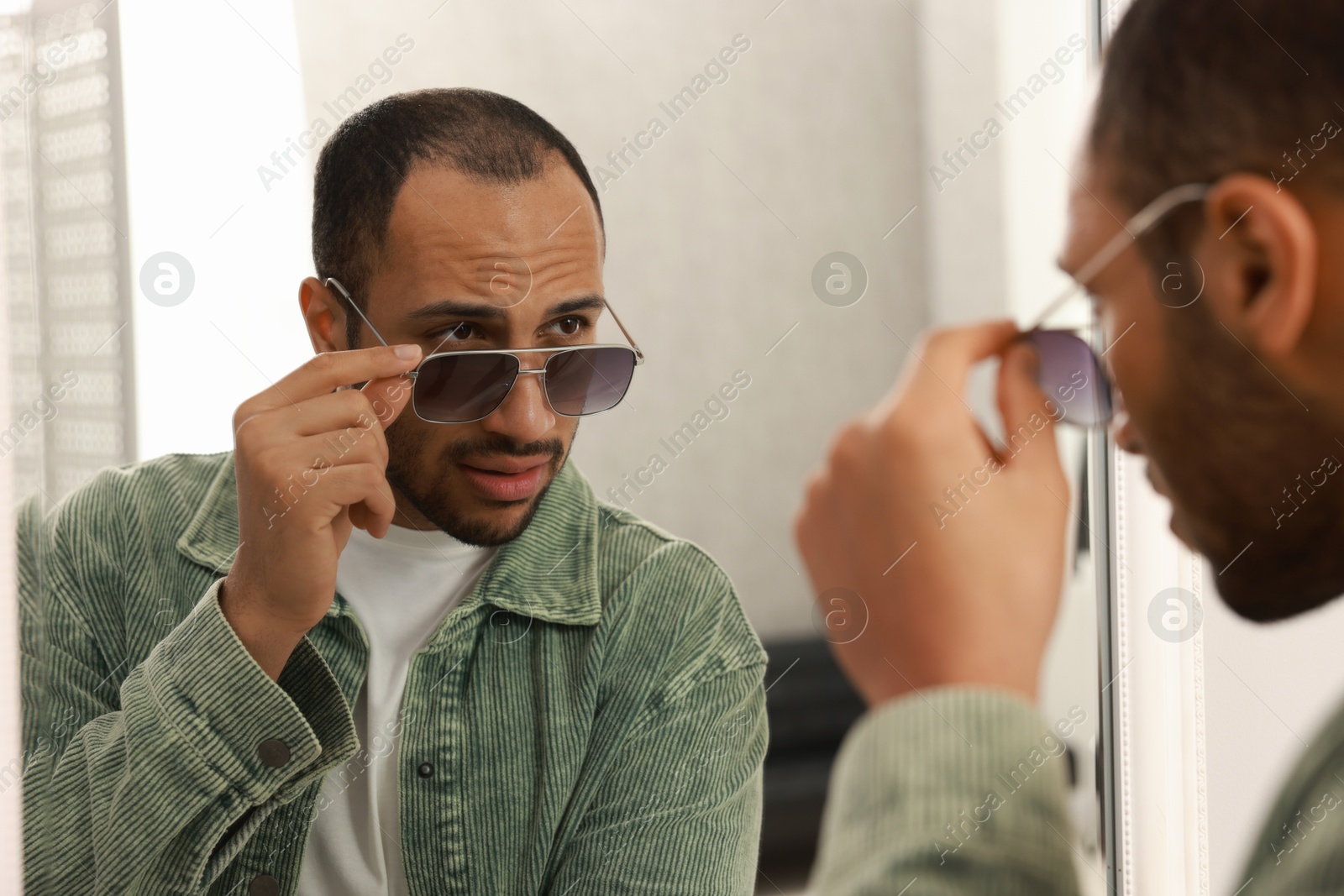 Photo of Handsome man looking at mirror at home