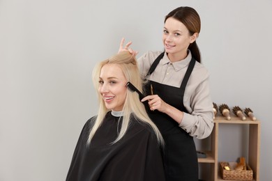 Photo of Professional hairdresser combing woman's hair in salon