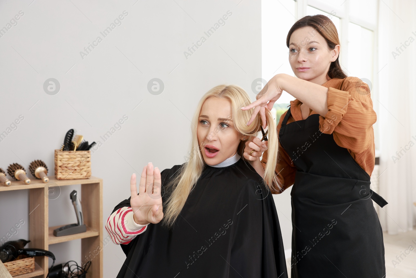 Photo of Hairdresser cutting client's hair with scissors in salon