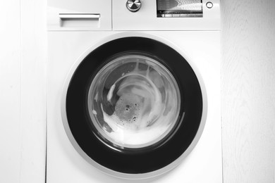 Photo of Washing machine with suds as background, closeup