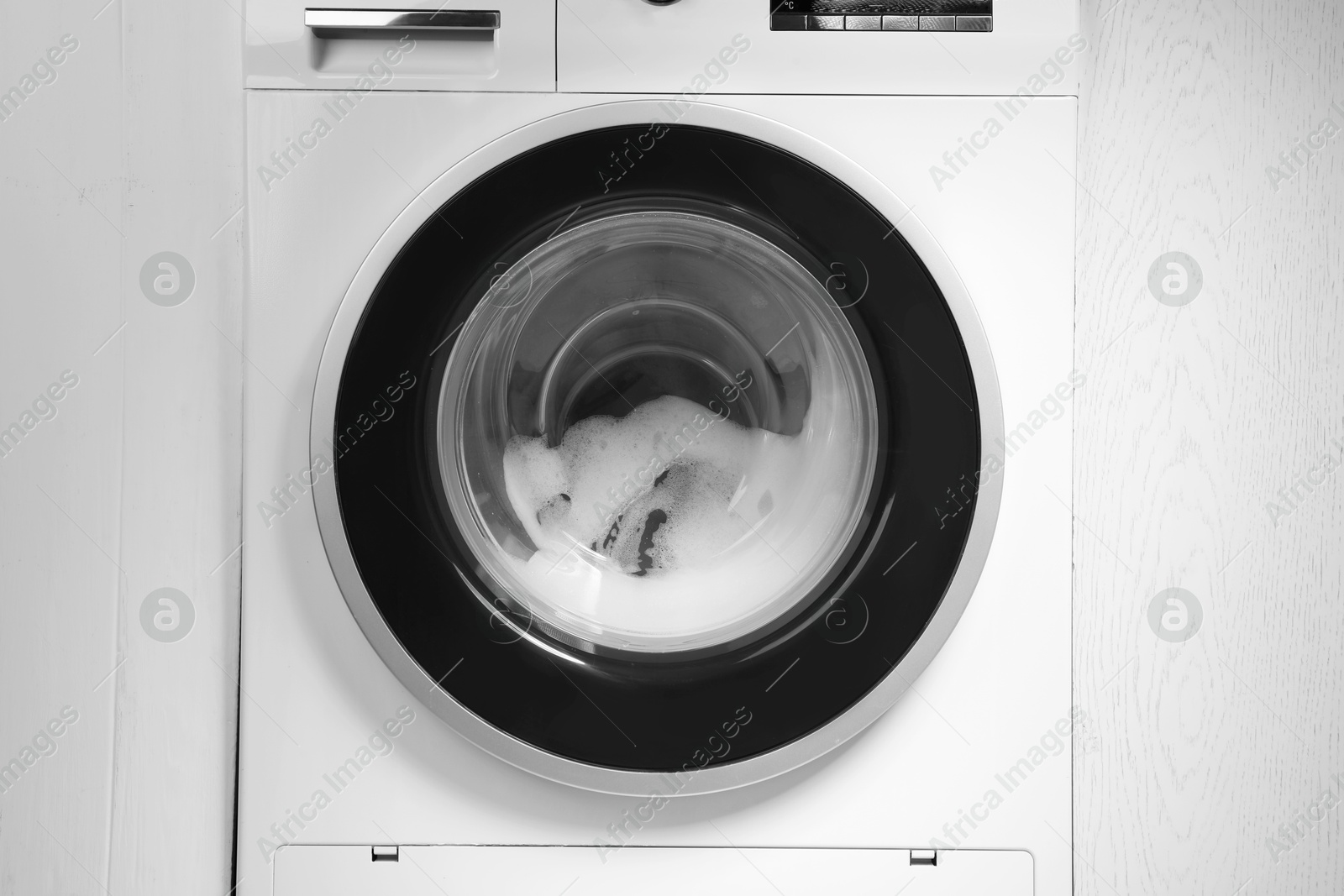 Photo of Washing machine with suds as background, closeup