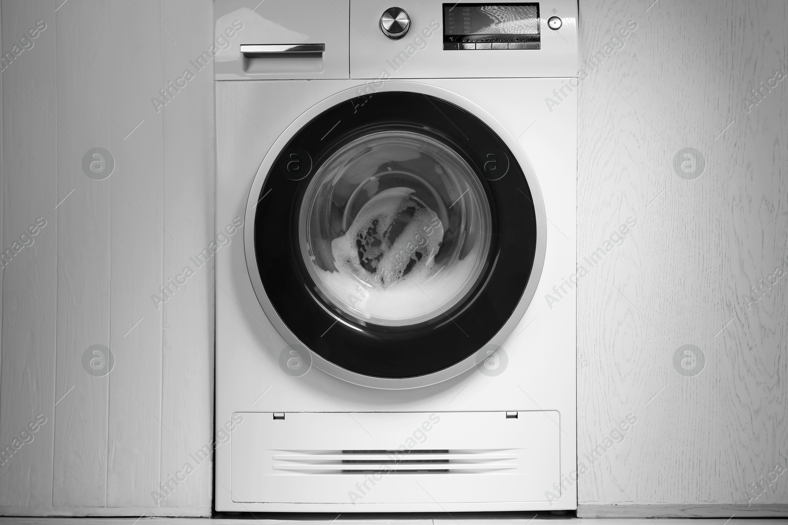 Photo of White washing machine with suds in bathroom