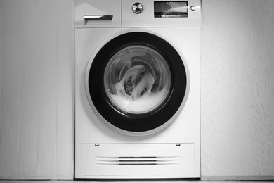 Photo of White washing machine with suds in bathroom